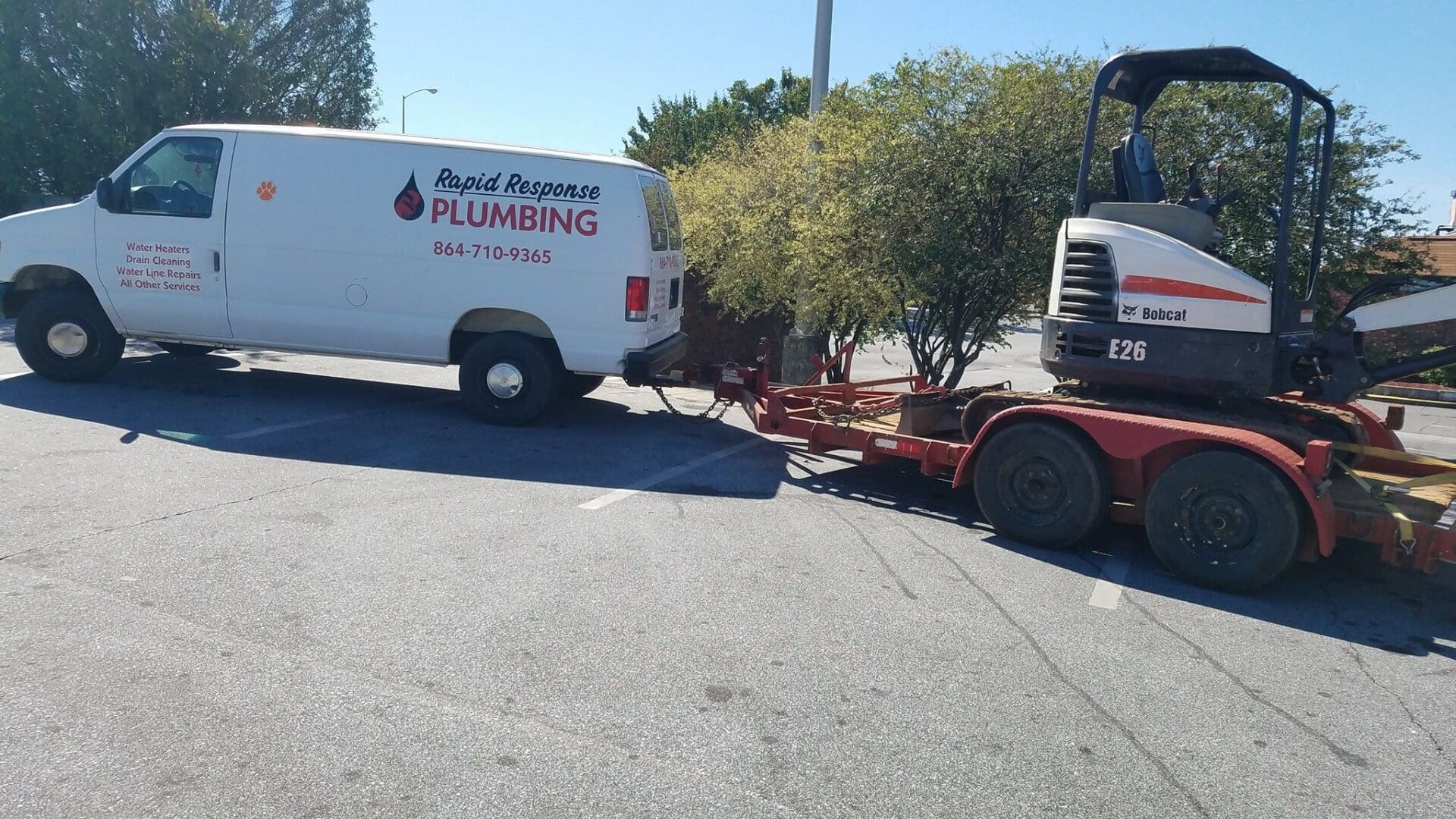 A white truck pulling a red trailer behind it.